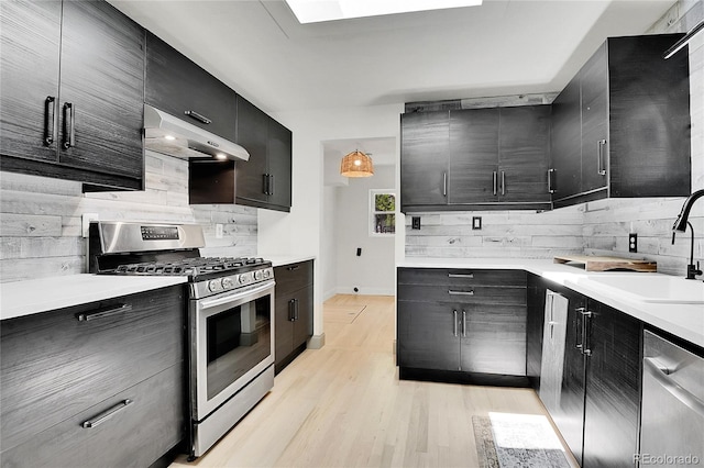 10887 Goodheart Ave, Conifer, CO 80433 - kitchen with appliances with stainless steel finishes, under cabinet range hood, tasteful backsplash, dark cabinetry, and light countertops