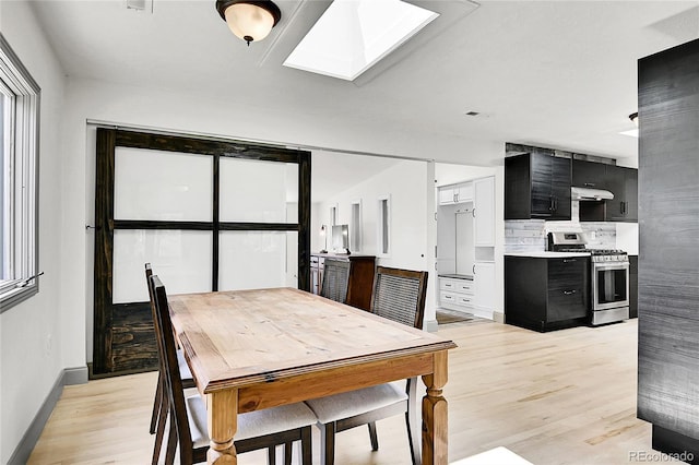 10887 Goodheart Ave, Conifer, CO 80433 - dining room featuring light wood finished floors, a skylight, and baseboards