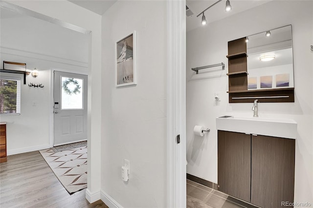 10887 Goodheart Ave, Conifer, CO 80433 - bathroom featuring vanity, baseboards, rail lighting, and wood finished floors