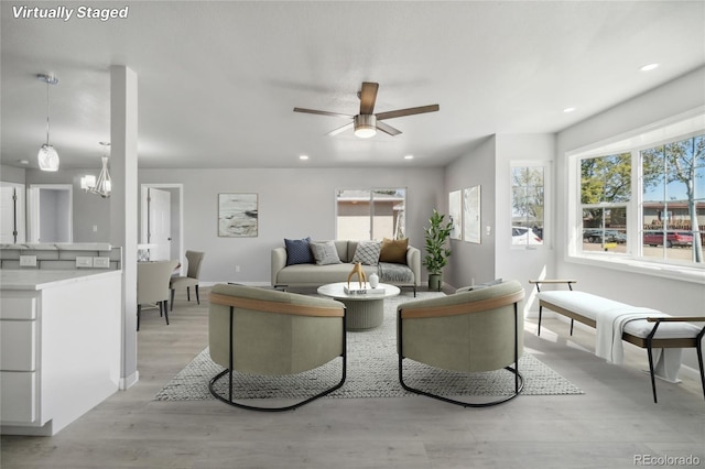 living room featuring ceiling fan with notable chandelier and light hardwood / wood-style floors