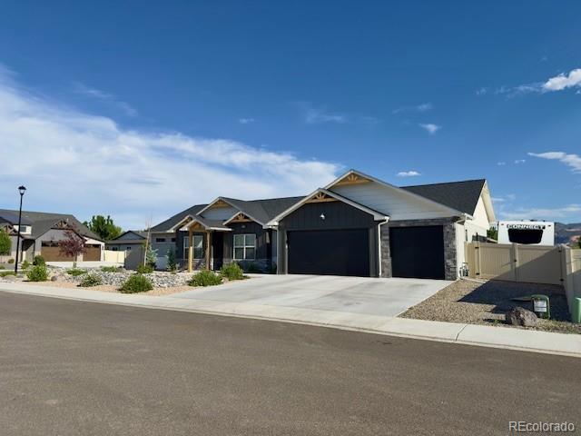 734 Flamecrest Dr, Fruita, CO 81521 - view of front of home with a garage, a gate, concrete driveway, a residential view, and stone siding