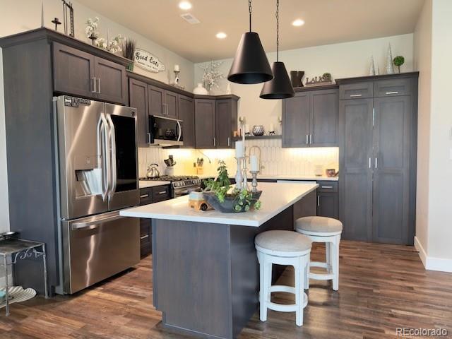734 Flamecrest Dr, Fruita, CO 81521 - kitchen with appliances with stainless steel finishes, dark wood-type flooring, light countertops, a kitchen island, and recessed lighting