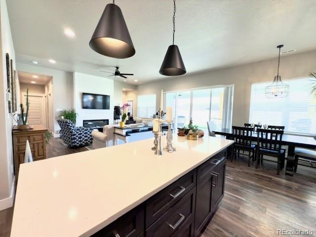 734 Flamecrest Dr, Fruita, CO 81521 - kitchen with dark wood-style flooring, light countertops, ceiling fan, a center island, and hanging light fixtures