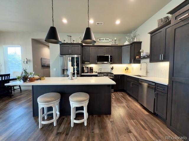 734 Flamecrest Dr, Fruita, CO 81521 - kitchen featuring stainless steel appliances, dark wood-type flooring, a kitchen island, decorative backsplash, and light countertops