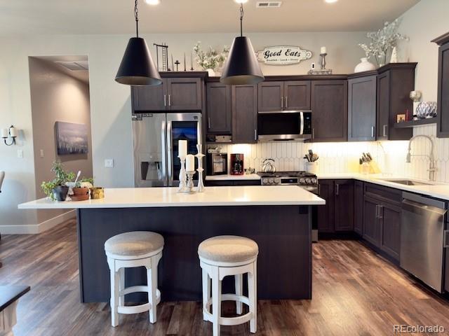734 Flamecrest Dr, Fruita, CO 81521 - kitchen featuring stainless steel appliances, a kitchen island, dark brown cabinets, decorative backsplash, and a breakfast bar