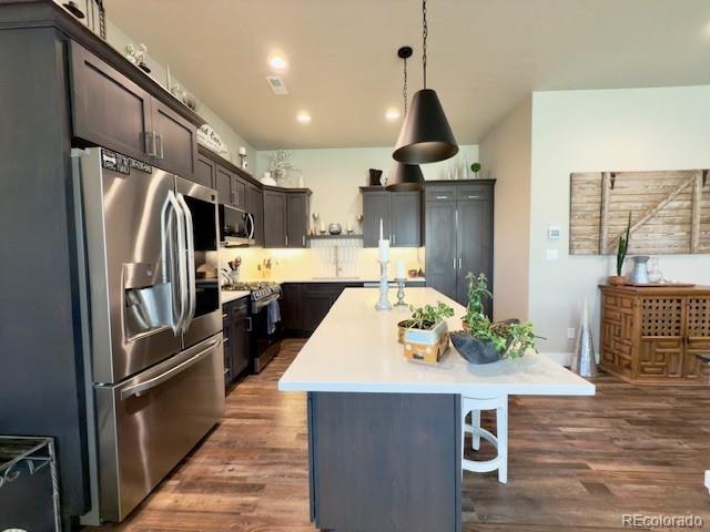 734 Flamecrest Dr, Fruita, CO 81521 - kitchen featuring stainless steel appliances, a center island, a breakfast bar area, dark wood-style flooring, and recessed lighting