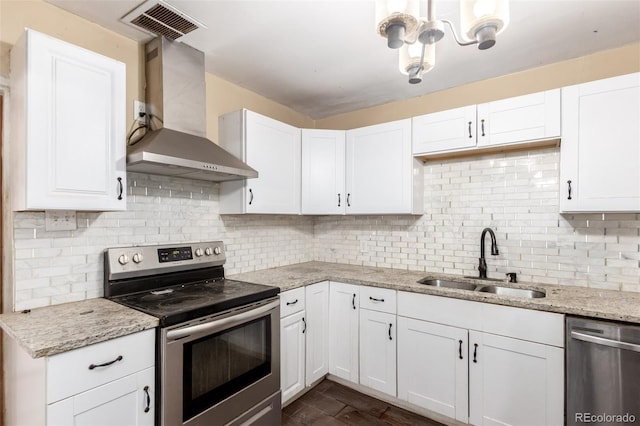 1151 Revere St, Aurora, CO 80011 - kitchen with appliances with stainless steel finishes, wall chimney range hood, a sink, white cabinets, and decorative backsplash