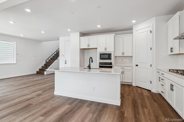 8462 Eagle River St, Littleton, CO 80125 - kitchen with light countertops, wood finished floors, stainless steel appliances, white cabinetry, and a sink