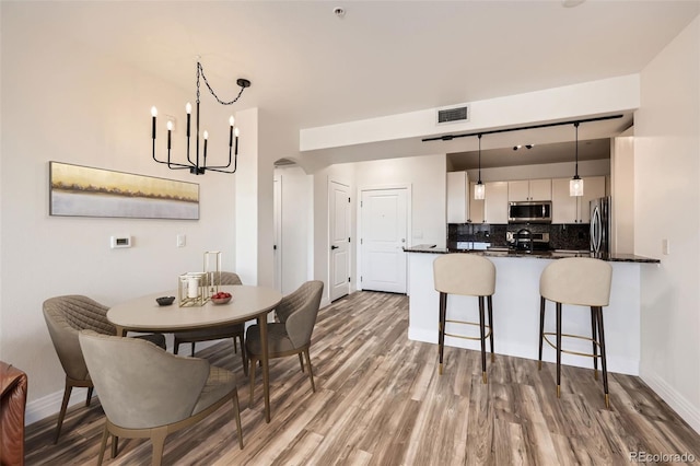 9079 E Panorama Cir Unit 419, Englewood, CO 80112 - dining room featuring wood finished floors, a chandelier, baseboards, and arched walkways