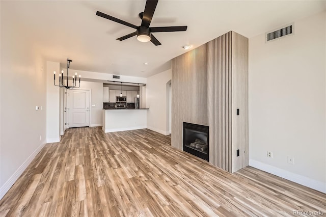 9079 E Panorama Cir Unit 419, Englewood, CO 80112 - unfurnished living room featuring light wood finished floors, ceiling fan, a chandelier, and baseboards