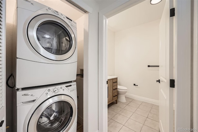 9079 E Panorama Cir Unit 419, Englewood, CO 80112 - washroom featuring stacked washer / drying machine, light tile patterned floors, and baseboards