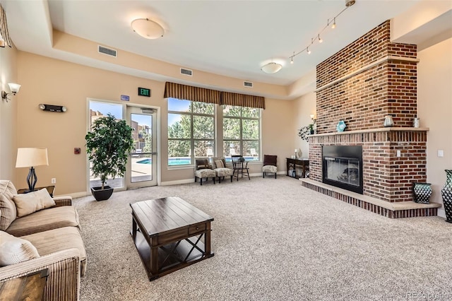 9079 E Panorama Cir Unit 419, Englewood, CO 80112 - carpeted living room featuring a fireplace, baseboards, a tray ceiling, and rail lighting