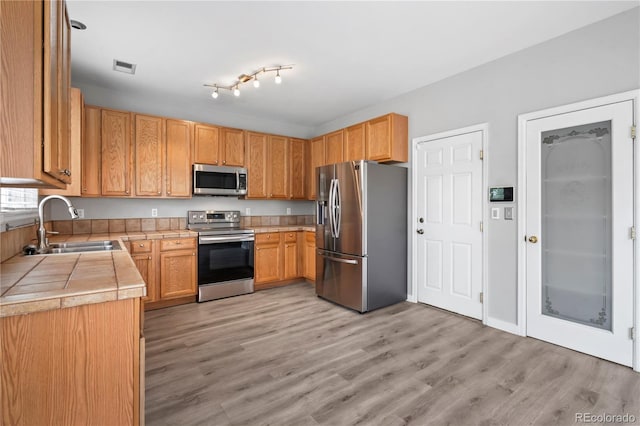 1160 S Fultondale Ct, Aurora, CO 80018 - kitchen with stainless steel appliances, a sink, tile counters, and light wood-style flooring