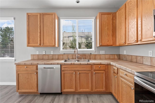 1160 S Fultondale Ct, Aurora, CO 80018 - kitchen featuring appliances with stainless steel finishes, a sink, tile countertops, and light wood finished floors