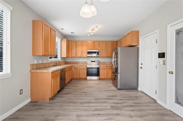 1160 S Fultondale Ct, Aurora, CO 80018 - kitchen with stainless steel appliances, a sink, light countertops, light wood-type flooring, and baseboards