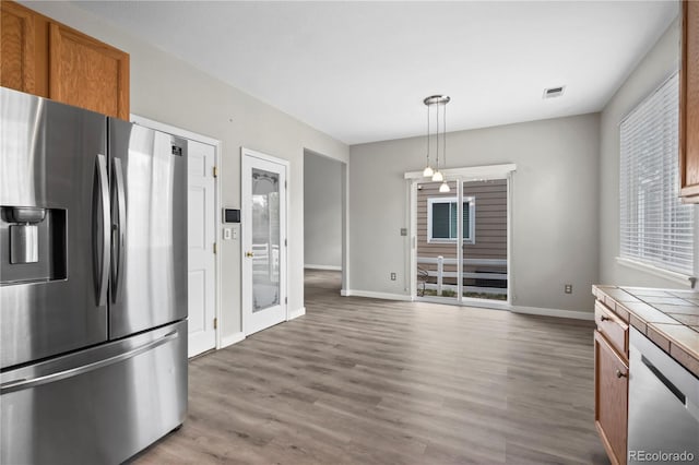 1160 S Fultondale Ct, Aurora, CO 80018 - kitchen with appliances with stainless steel finishes, tile countertops, brown cabinets, baseboards, and wood finished floors