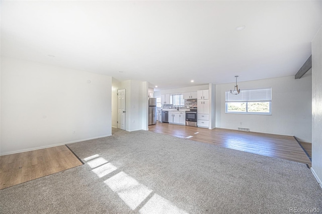 unfurnished living room featuring a chandelier and light hardwood / wood-style flooring