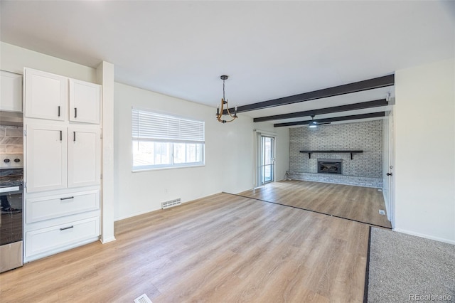 unfurnished living room with light wood-type flooring, a brick fireplace, brick wall, ceiling fan, and beam ceiling