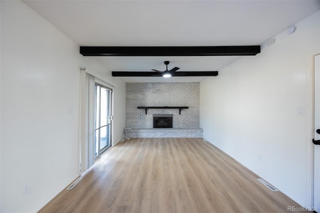 unfurnished living room with ceiling fan, beamed ceiling, light hardwood / wood-style floors, and a brick fireplace