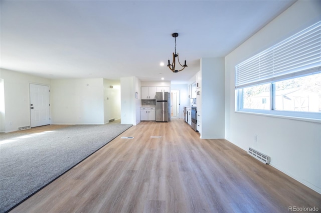 unfurnished living room featuring light hardwood / wood-style flooring and a notable chandelier