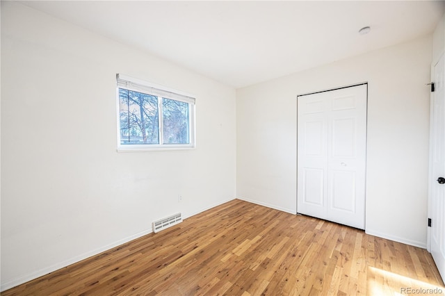 unfurnished bedroom with light wood-type flooring and a closet