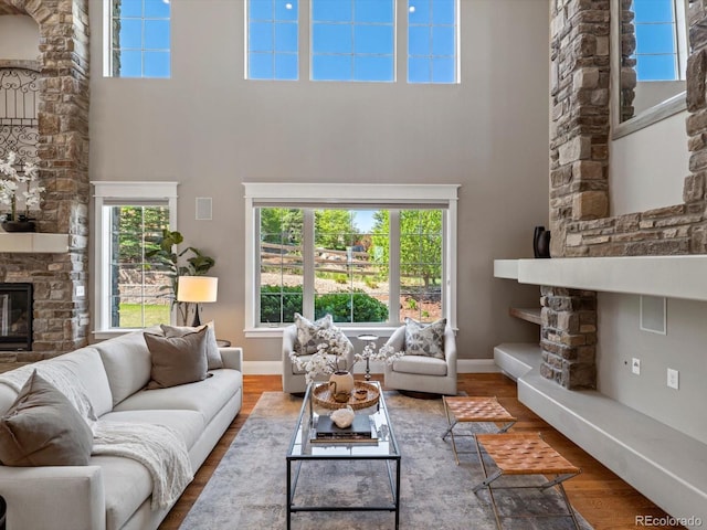 6995 S Ensenada St, Aurora, CO 80016 - living room featuring a high ceiling, wood finished floors, a stone fireplace, and baseboards