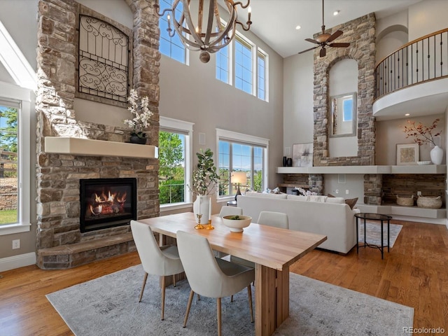 6995 S Ensenada St, Aurora, CO 80016 - dining room with a stone fireplace, a high ceiling, wood finished floors, a ceiling fan, and baseboards