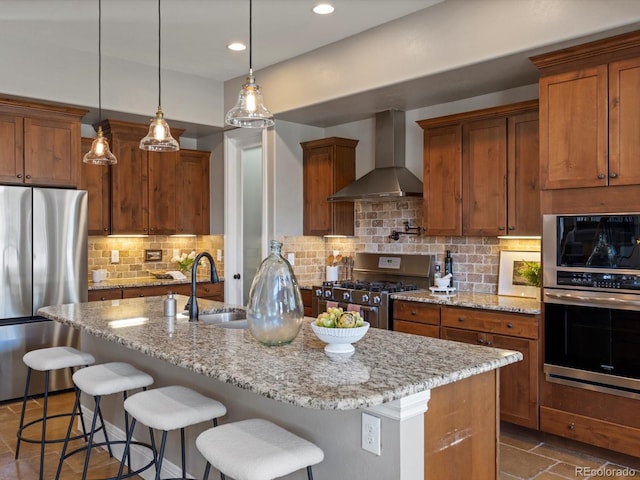 6995 S Ensenada St, Aurora, CO 80016 - kitchen featuring stainless steel appliances, wall chimney exhaust hood, a sink, light stone counters, and a breakfast bar area