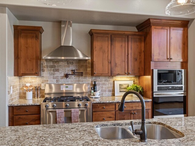 6995 S Ensenada St, Aurora, CO 80016 - kitchen with wall chimney exhaust hood, appliances with stainless steel finishes, a sink, and light stone countertops