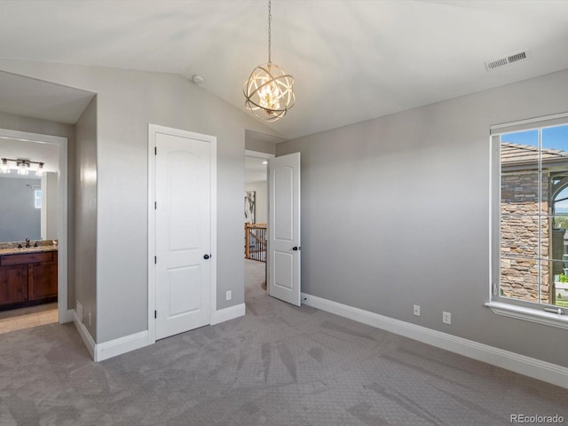 6995 S Ensenada St, Aurora, CO 80016 - unfurnished bedroom featuring a chandelier, light colored carpet, vaulted ceiling, ensuite bathroom, and a sink