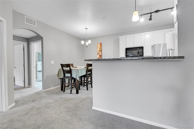 17442 Nature Walk Trl Unit 105, Parker, CO 80134 - kitchen featuring black microwave, refrigerator, carpet floors, white cabinets, and arched walkways