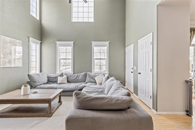 living room featuring a towering ceiling and light wood-type flooring