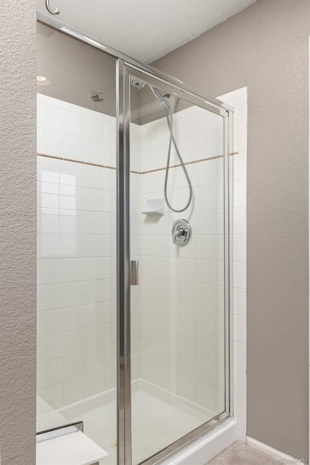 bathroom with a shower with shower door and a textured ceiling