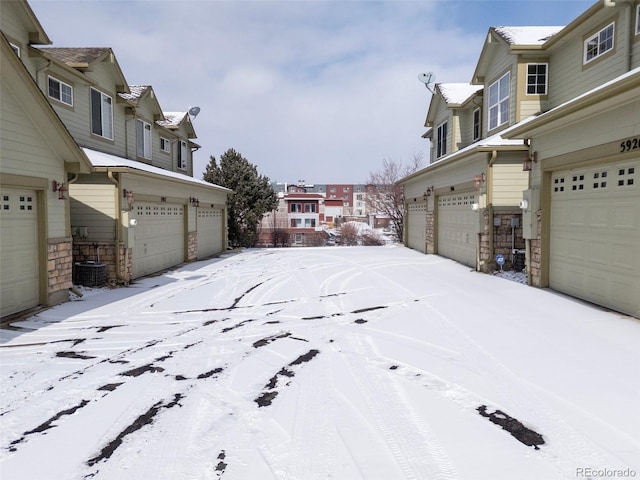 snowy yard with a garage and central air condition unit