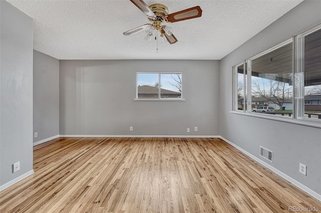 empty room with visible vents, baseboards, a ceiling fan, a textured ceiling, and wood finished floors
