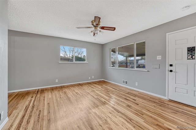 interior space featuring ceiling fan, a textured ceiling, visible vents, wood finished floors, and baseboards