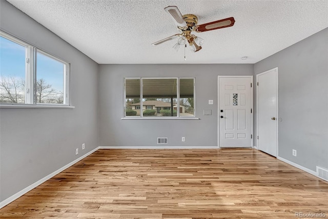 empty room featuring visible vents, a textured ceiling, a ceiling fan, and wood finished floors