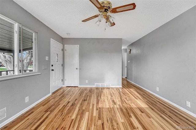 unfurnished living room with baseboards, a textured ceiling, visible vents, ceiling fan, and wood finished floors