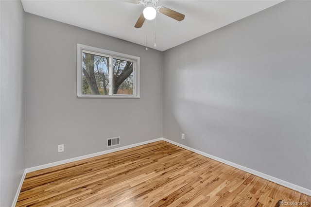 spare room featuring visible vents, baseboards, a ceiling fan, and wood finished floors