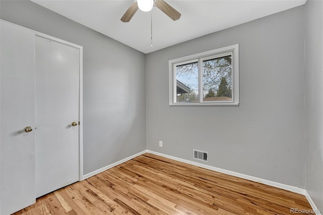 unfurnished bedroom with wood finished floors, ceiling fan, baseboards, and visible vents