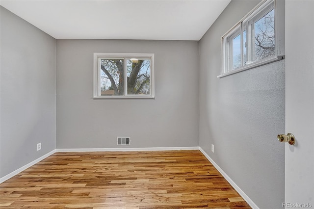 unfurnished room with a wealth of natural light, wood finished floors, and baseboards