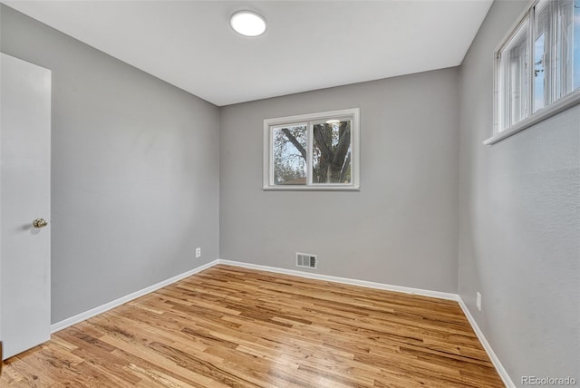 empty room with light wood-style floors, baseboards, and visible vents