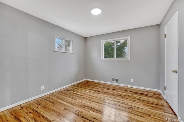 spare room with visible vents, a wealth of natural light, wood finished floors, and baseboards