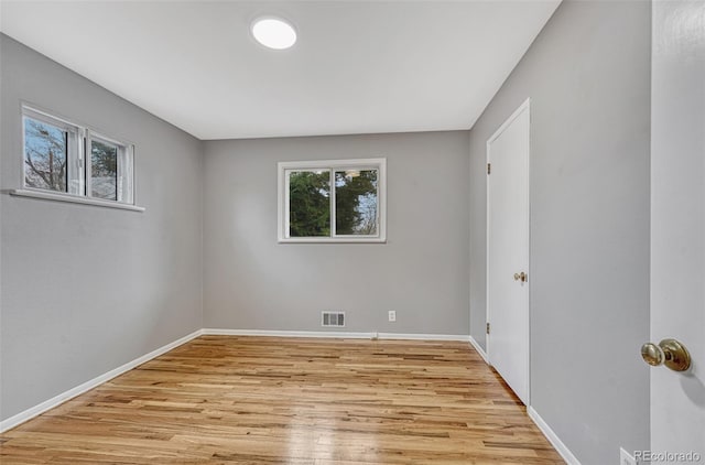 unfurnished room featuring visible vents, light wood-style flooring, and baseboards
