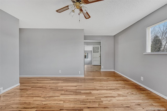 unfurnished room with light wood-type flooring, a textured ceiling, a ceiling fan, visible vents, and baseboards