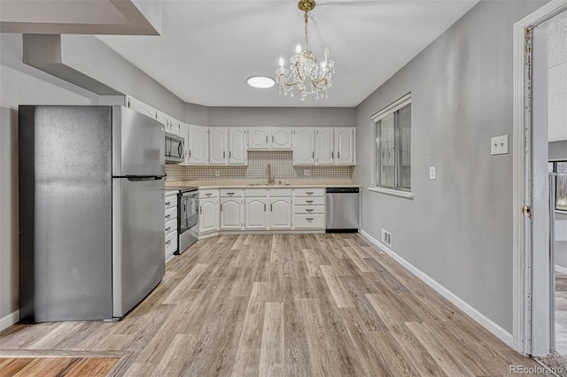 kitchen with light wood-style floors, appliances with stainless steel finishes, light countertops, and white cabinetry