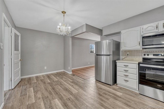 kitchen featuring light countertops, light wood-type flooring, an inviting chandelier, and stainless steel appliances
