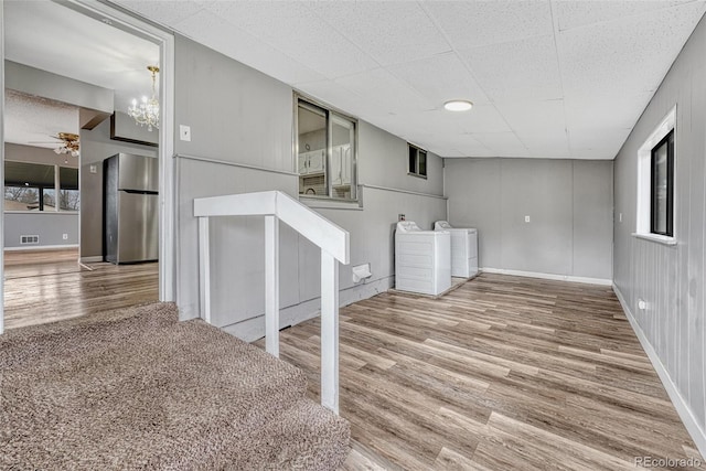 basement with visible vents, freestanding refrigerator, a ceiling fan, independent washer and dryer, and wood finished floors