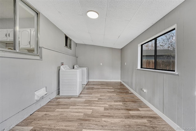 below grade area featuring independent washer and dryer, a drop ceiling, and wood finished floors