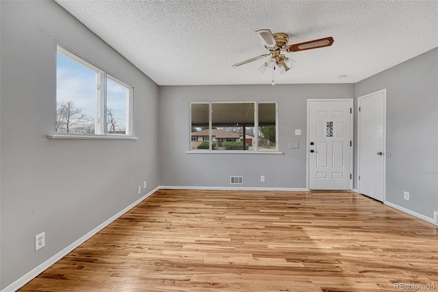 unfurnished room with visible vents, baseboards, a ceiling fan, a textured ceiling, and wood finished floors